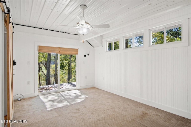 spare room featuring a barn door, a healthy amount of sunlight, and ceiling fan