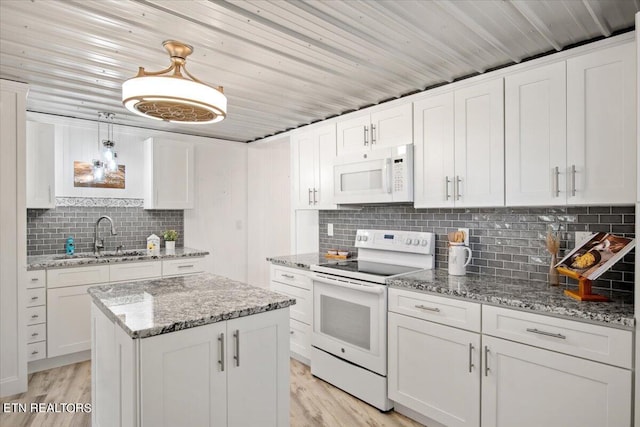 kitchen featuring light wood finished floors, decorative backsplash, white cabinets, white appliances, and a sink