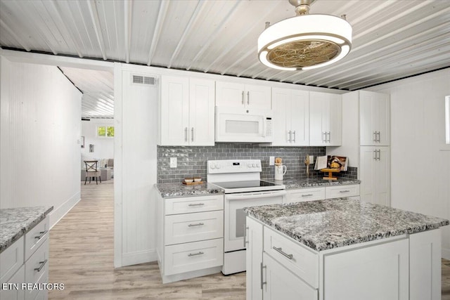 kitchen featuring light stone countertops, white cabinetry, a kitchen island, and white appliances