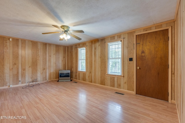 foyer entrance featuring wood walls, a textured ceiling, ceiling fan, and light hardwood / wood-style floors