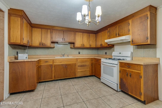 kitchen featuring white range with gas cooktop, an inviting chandelier, sink, light tile patterned floors, and a textured ceiling