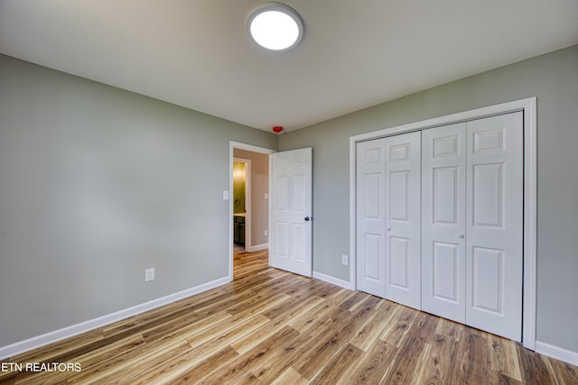 unfurnished bedroom with light hardwood / wood-style flooring and a closet