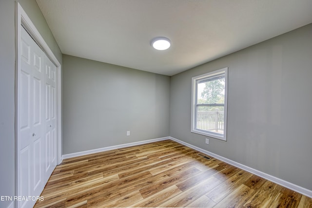 unfurnished bedroom with light wood-type flooring and a closet