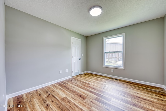 empty room featuring a textured ceiling and light wood-type flooring