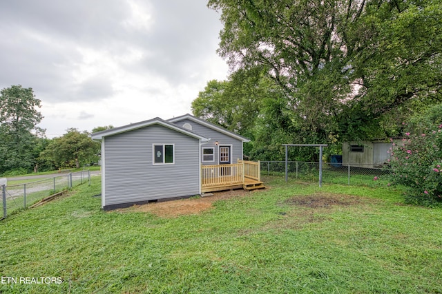 back of house with a wooden deck and a lawn