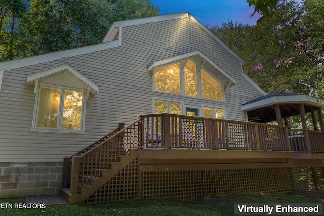 back house at dusk featuring a gazebo and a deck