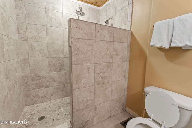 bathroom featuring toilet, tile patterned flooring, and a tile shower