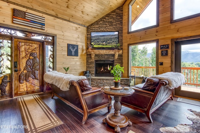 living room with high vaulted ceiling, a stone fireplace, wooden walls, and hardwood / wood-style floors