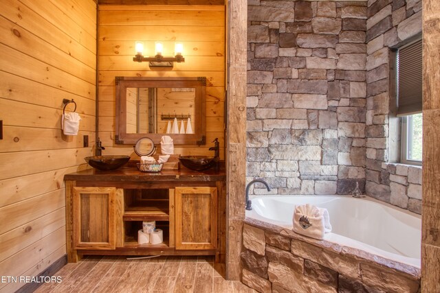 bathroom featuring wood walls, tiled tub, wood-type flooring, and double sink vanity