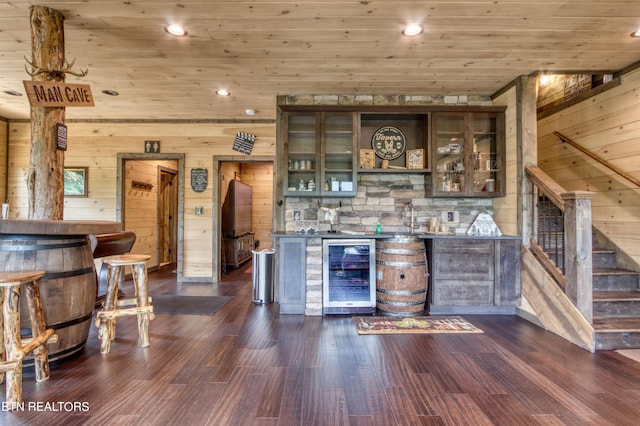 bar featuring wooden walls, wood ceiling, dark brown cabinetry, dark hardwood / wood-style floors, and wine cooler