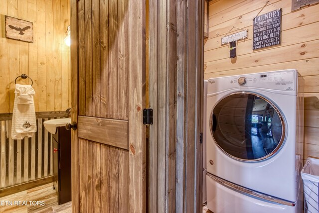 laundry area featuring washer / clothes dryer, wood walls, and light wood-type flooring