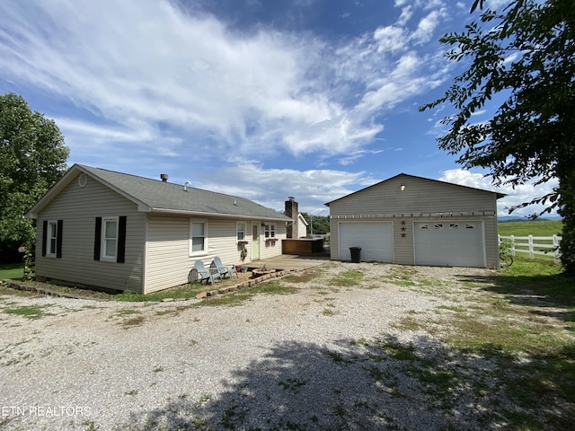 view of property exterior featuring a garage, an outbuilding, and a deck