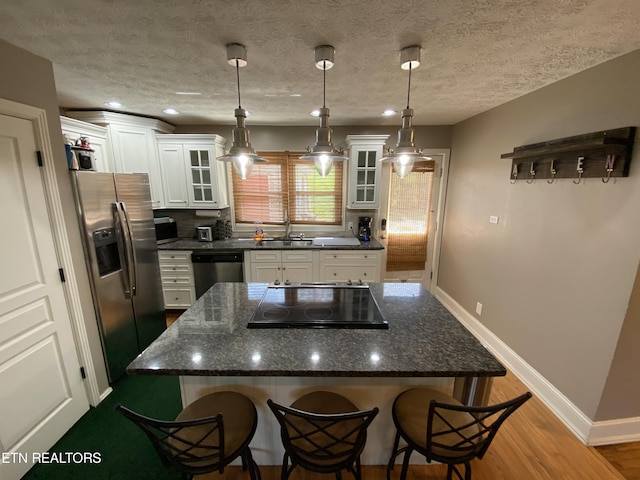 kitchen featuring pendant lighting, a breakfast bar, appliances with stainless steel finishes, white cabinets, and decorative backsplash