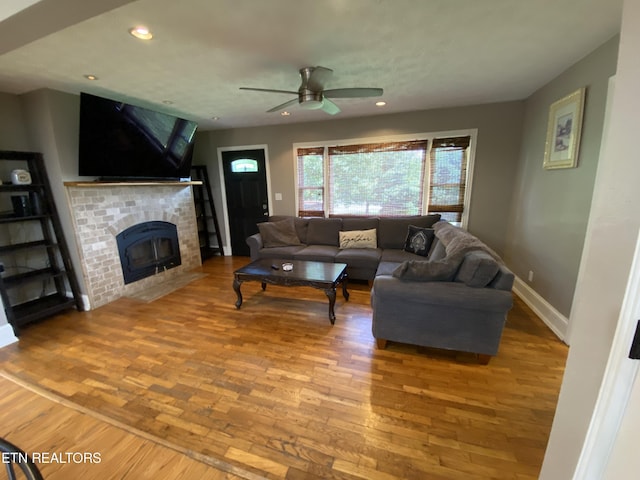 living room featuring a brick fireplace, hardwood / wood-style floors, and ceiling fan