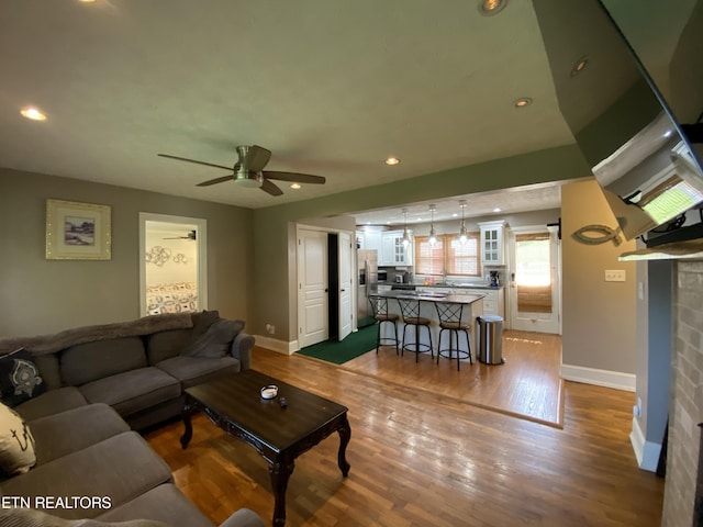 living room with hardwood / wood-style flooring, ceiling fan, and a fireplace