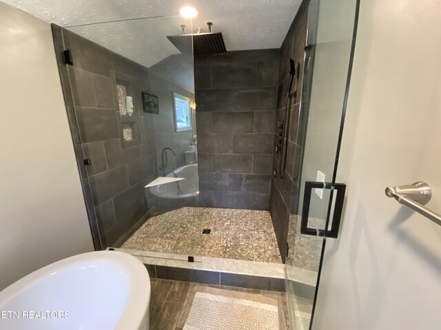 bathroom with walk in shower and a textured ceiling