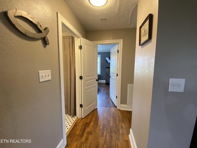 hall featuring dark hardwood / wood-style floors and a textured ceiling