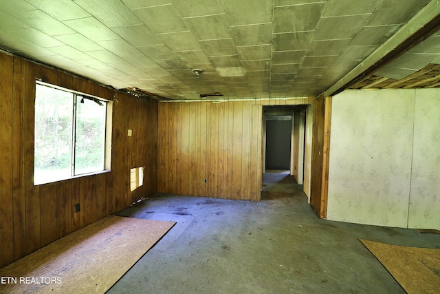 empty room with wood walls and concrete flooring