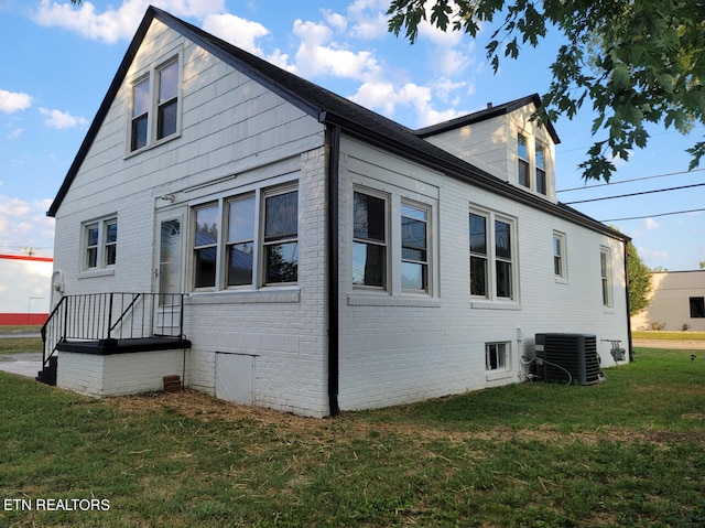 view of side of property with central AC unit and a lawn