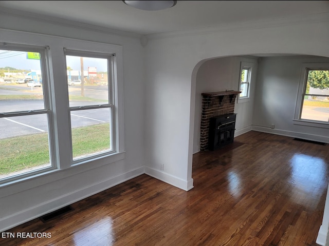 unfurnished living room featuring crown molding, a healthy amount of sunlight, a fireplace, and dark hardwood / wood-style flooring