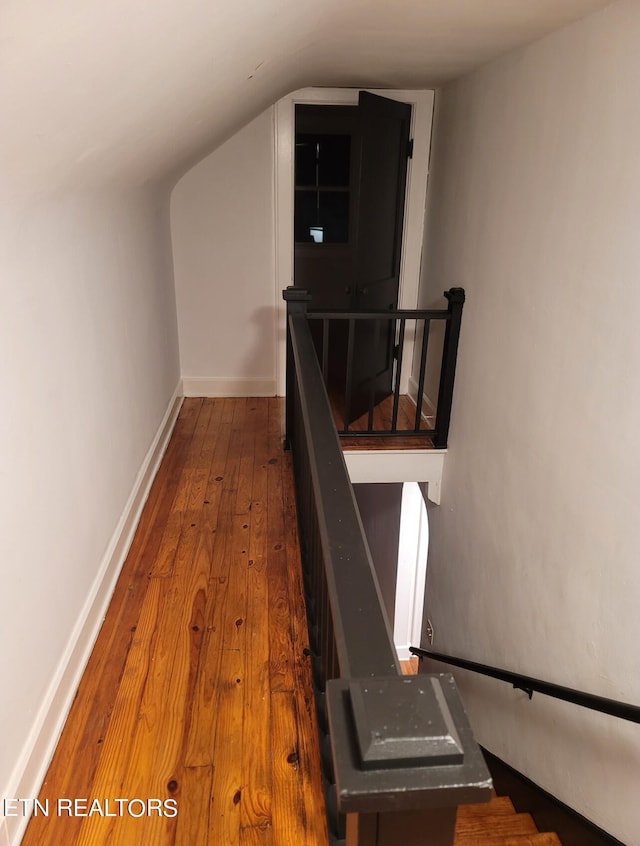 hallway with lofted ceiling and hardwood / wood-style flooring