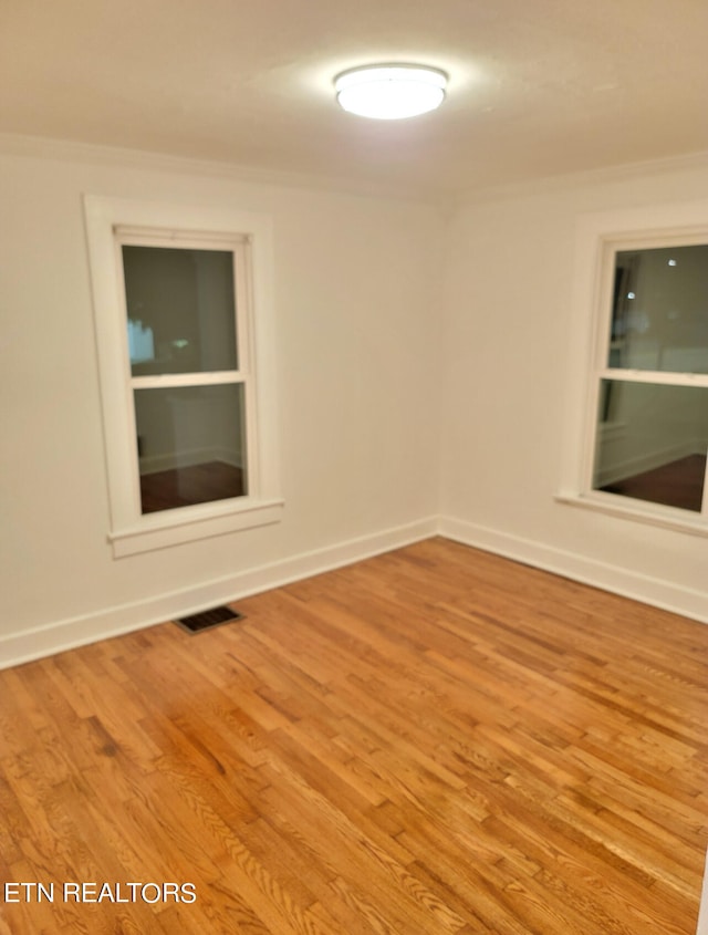 spare room featuring crown molding and light wood-type flooring