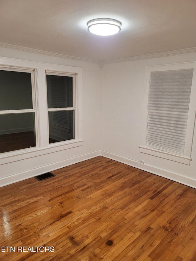 empty room with crown molding and wood-type flooring