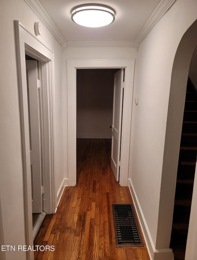 hallway with dark wood-type flooring and crown molding