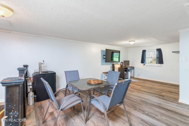 dining room featuring a textured ceiling, hardwood / wood-style flooring, and crown molding