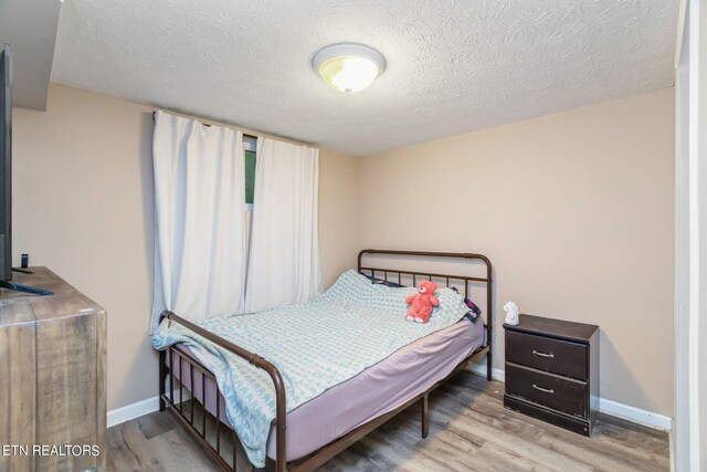 bedroom with a textured ceiling and light hardwood / wood-style flooring