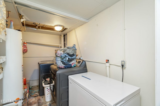 laundry room with tile patterned flooring, washing machine and dryer, and water heater