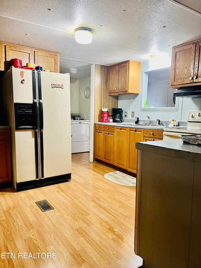 kitchen with light hardwood / wood-style floors, washer / clothes dryer, a textured ceiling, and white appliances