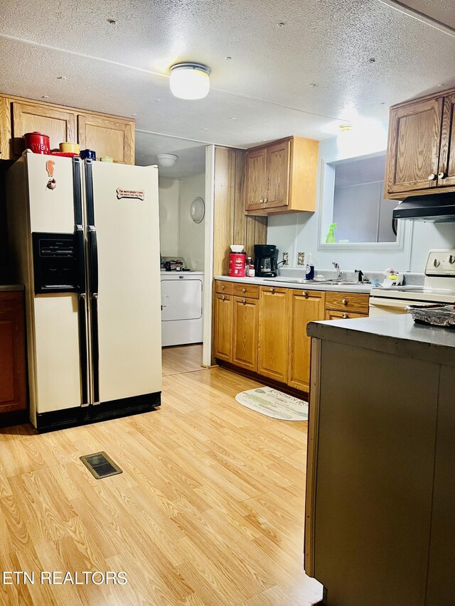 kitchen with white appliances, visible vents, washer / dryer, light wood-style flooring, and under cabinet range hood