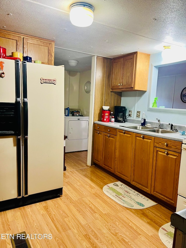 kitchen with separate washer and dryer, white refrigerator, light hardwood / wood-style flooring, and sink