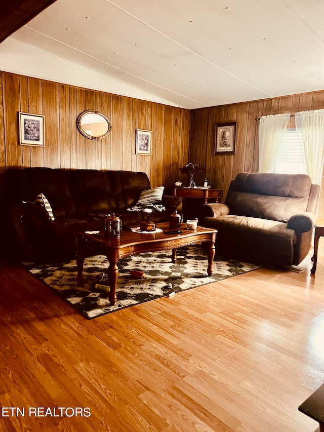 living room featuring wooden walls, light hardwood / wood-style flooring, and vaulted ceiling