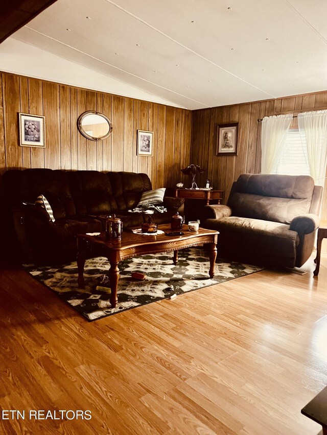 living area featuring vaulted ceiling, wood walls, and wood finished floors