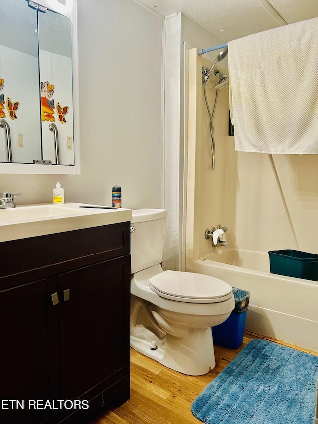 bathroom featuring vanity, toilet, wood finished floors, and shower / washtub combination