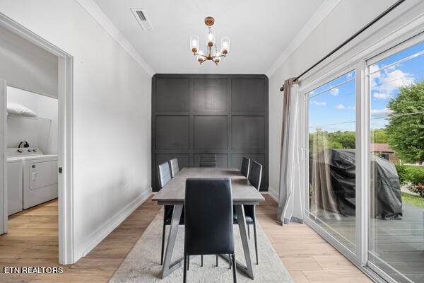 dining area featuring a notable chandelier, ornamental molding, washer and clothes dryer, and light hardwood / wood-style floors