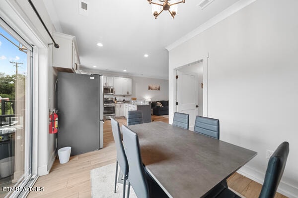 dining area featuring an inviting chandelier, light hardwood / wood-style floors, and crown molding