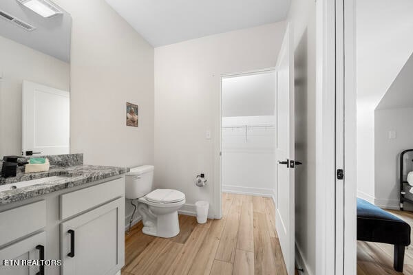 bathroom featuring toilet, vanity, and hardwood / wood-style flooring