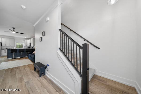 stairway featuring ceiling fan and light hardwood / wood-style floors