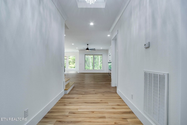 corridor with light hardwood / wood-style flooring and crown molding