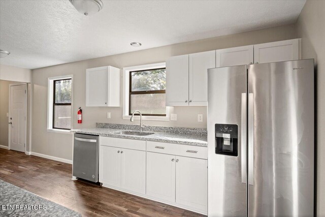 kitchen with sink, a textured ceiling, appliances with stainless steel finishes, dark hardwood / wood-style floors, and white cabinets