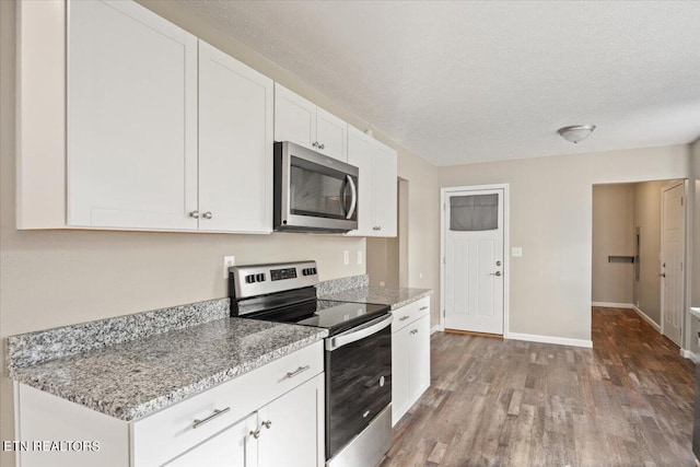 kitchen featuring white cabinetry, light stone counters, wood-type flooring, a textured ceiling, and stainless steel appliances