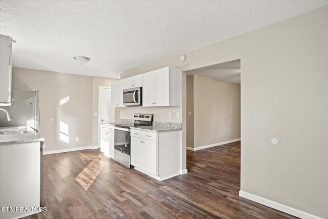 kitchen with sink, white cabinetry, dark hardwood / wood-style flooring, stainless steel appliances, and light stone countertops