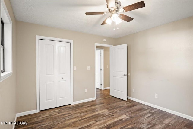 unfurnished bedroom featuring dark wood-type flooring, a textured ceiling, ceiling fan, and a closet