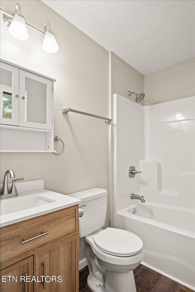 full bathroom featuring bathtub / shower combination, toilet, wood-type flooring, a textured ceiling, and vanity