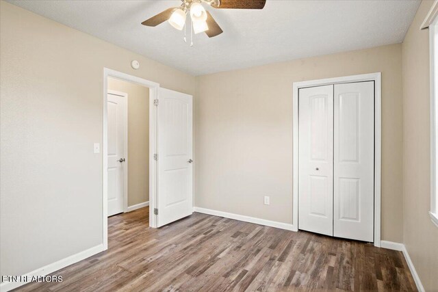 unfurnished bedroom featuring hardwood / wood-style flooring, ceiling fan, and a closet