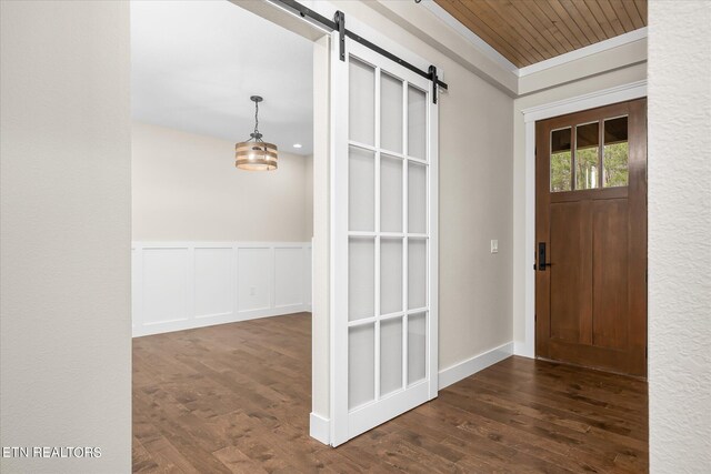entrance foyer featuring dark hardwood / wood-style flooring, ornamental molding, and a barn door