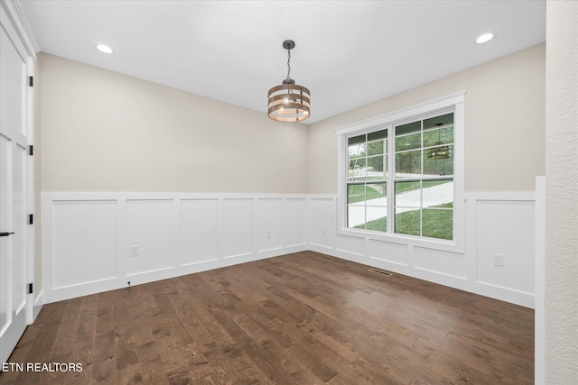 unfurnished room featuring a chandelier and dark hardwood / wood-style floors